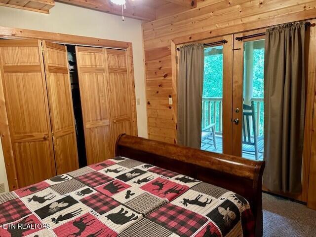 carpeted bedroom featuring wooden walls and a closet