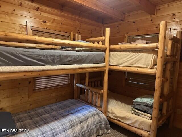 bedroom with wooden ceiling, beamed ceiling, and wood walls