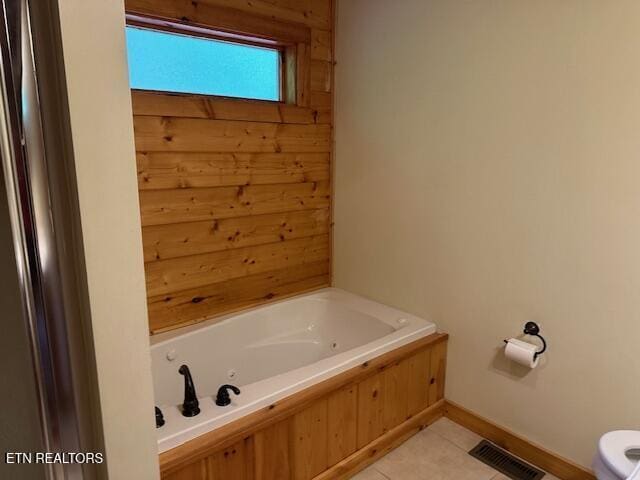 bathroom with tile patterned flooring, toilet, baseboards, a tub with jets, and visible vents