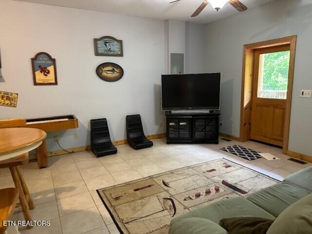 tiled living area with baseboards and a ceiling fan