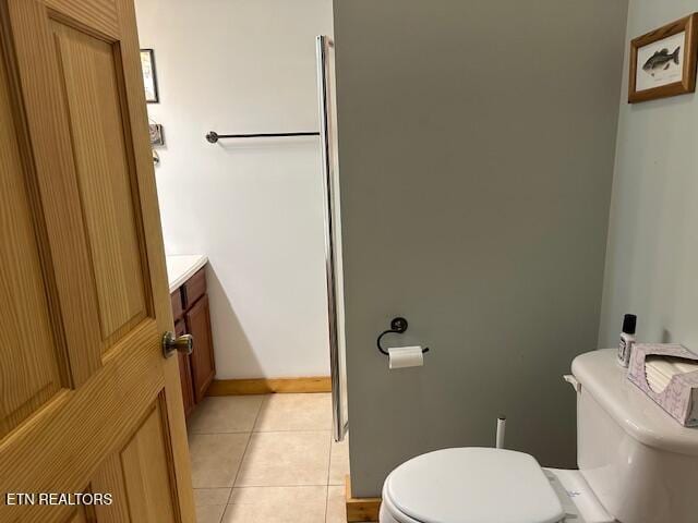 bathroom featuring toilet, baseboards, tile patterned flooring, and vanity
