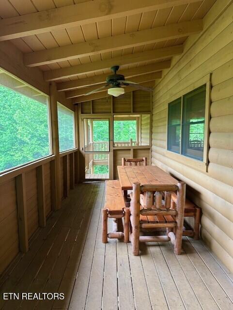 sunroom / solarium featuring outdoor dining space, ceiling fan, a healthy amount of sunlight, and beamed ceiling