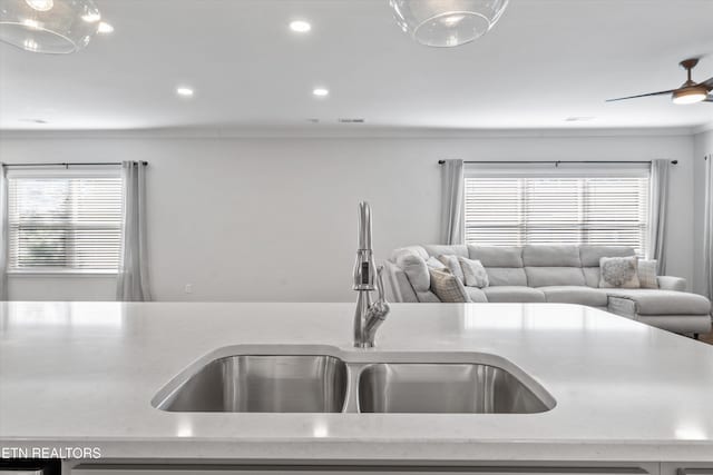 kitchen with ornamental molding, a sink, light stone counters, open floor plan, and recessed lighting