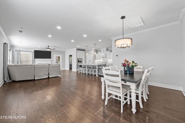 dining area with visible vents, ceiling fan with notable chandelier, crown molding, baseboards, and dark wood-style flooring