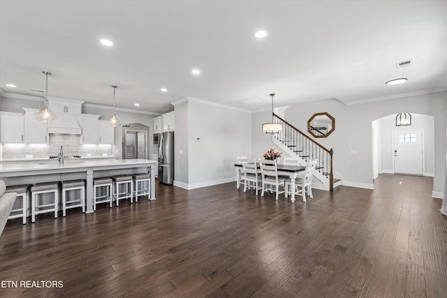 dining room with stairs, visible vents, arched walkways, and dark wood-style flooring