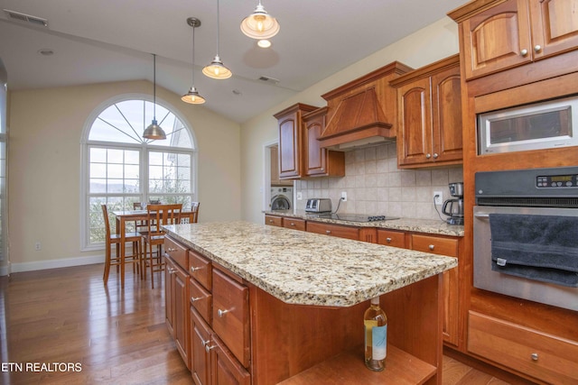 107 Sunny St, Sharps Chapel, TN 37866 - kitchen with stainless steel appliances, vaulted ceiling, wood finished floors, light stone countertops, and premium range hood