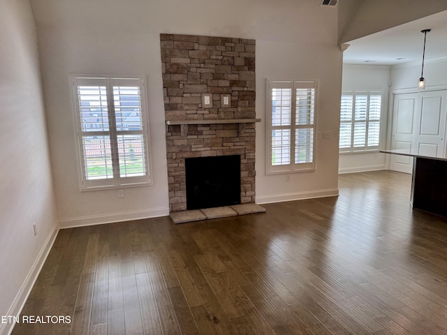 unfurnished living room with dark wood finished floors, baseboards, a fireplace, and ornamental molding