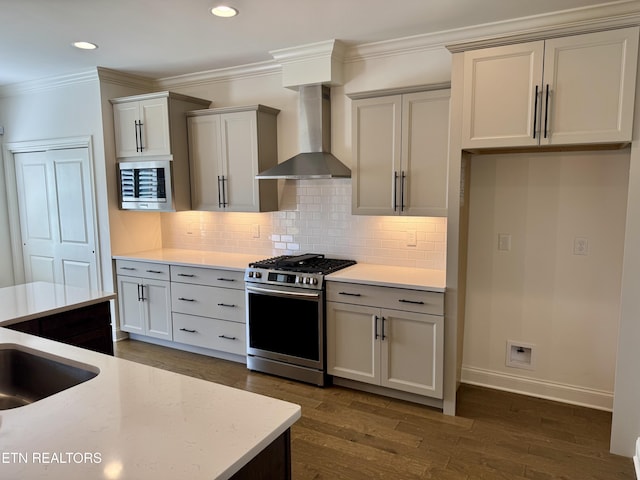 kitchen featuring backsplash, appliances with stainless steel finishes, dark wood finished floors, wall chimney range hood, and ornamental molding