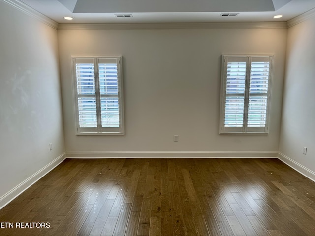 spare room featuring dark wood finished floors, baseboards, visible vents, and crown molding