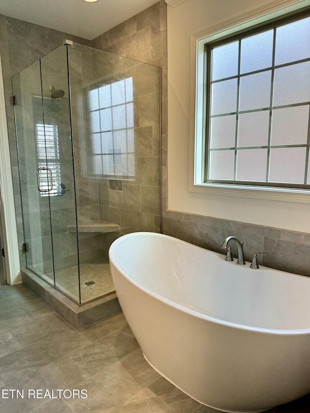 full bathroom with tile walls, a soaking tub, and a shower stall
