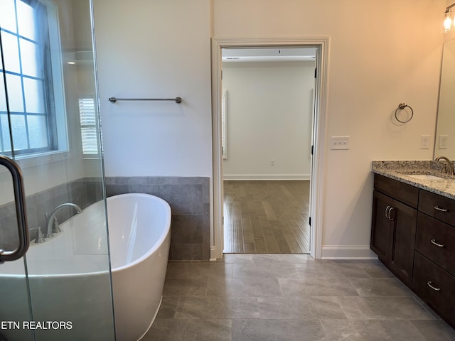 full bathroom with a soaking tub, tile walls, vanity, and tile patterned floors