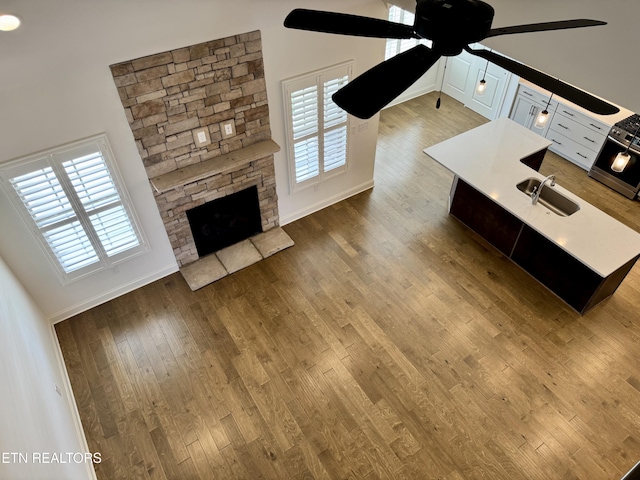 unfurnished living room with a wealth of natural light, hardwood / wood-style flooring, a sink, and a ceiling fan
