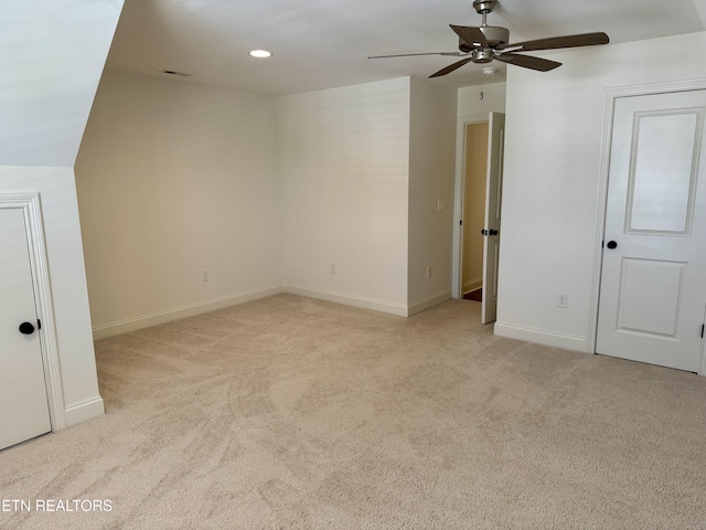 interior space featuring a ceiling fan, baseboards, and light colored carpet
