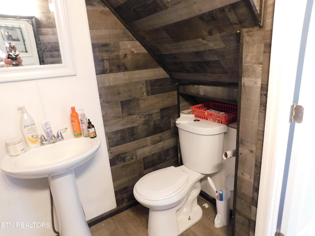 half bath featuring wooden walls and toilet