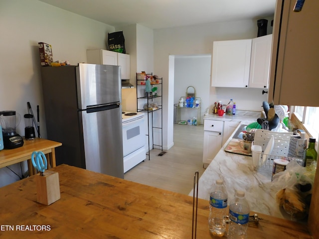 kitchen featuring white cabinetry, light wood-style flooring, freestanding refrigerator, and white range with electric cooktop