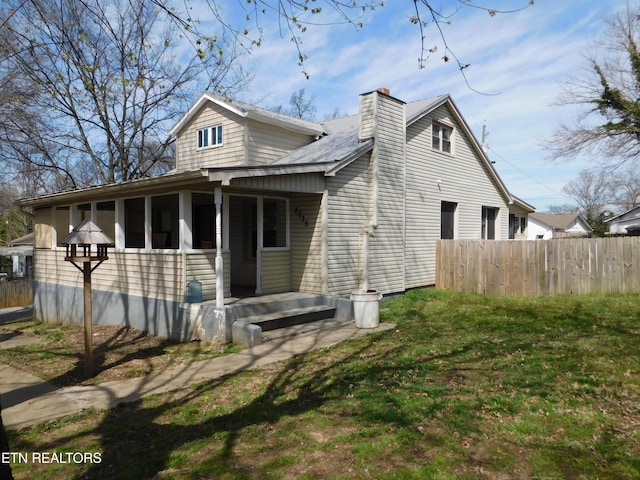 view of property exterior with fence, a chimney, a lawn, and a sunroom