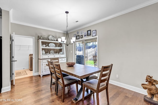 dining space featuring an inviting chandelier, crown molding, baseboards, and wood-type flooring