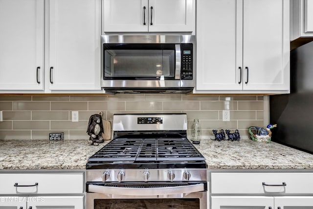 kitchen with stainless steel appliances, light stone countertops, decorative backsplash, and white cabinetry