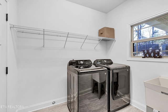 laundry area featuring laundry area, washer and dryer, baseboards, and a sink