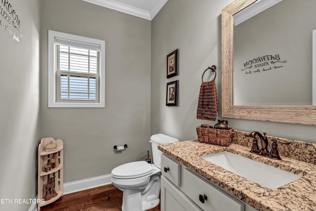 bathroom featuring toilet, ornamental molding, wood finished floors, baseboards, and vanity