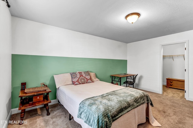 carpeted bedroom featuring a spacious closet, a closet, and baseboards
