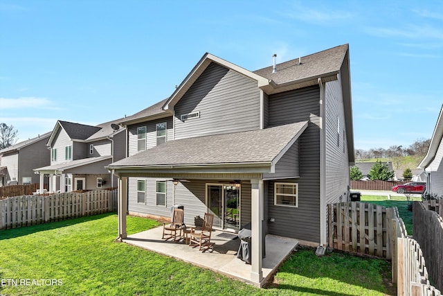 rear view of property with a patio, a ceiling fan, a yard, a fenced backyard, and a shingled roof