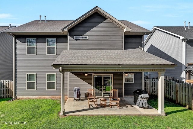 back of house featuring a patio area, a lawn, and roof with shingles