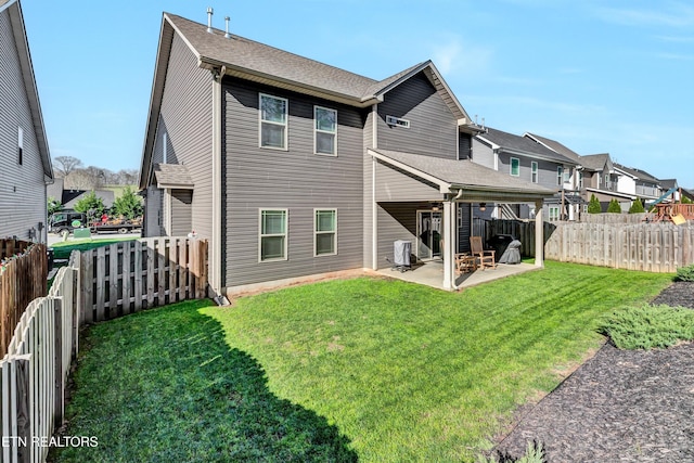 back of house with a yard, a patio area, a fenced backyard, and a shingled roof