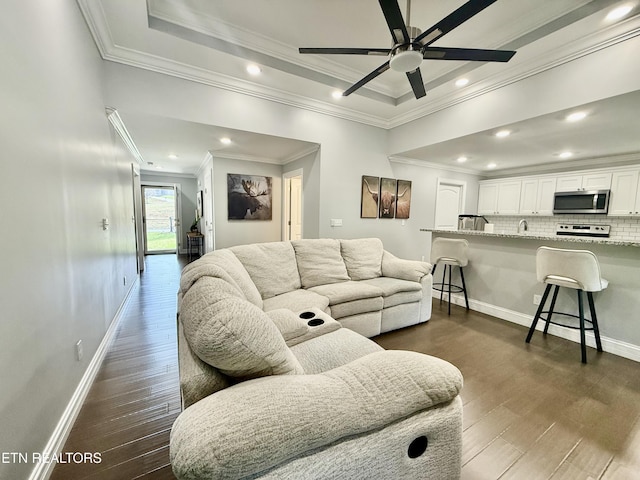 living area featuring dark wood-type flooring, baseboards, and ceiling fan