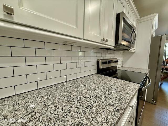 kitchen with dark wood-type flooring, light stone counters, white cabinetry, appliances with stainless steel finishes, and decorative backsplash