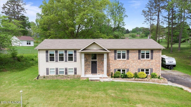bi-level home with brick siding and a front yard