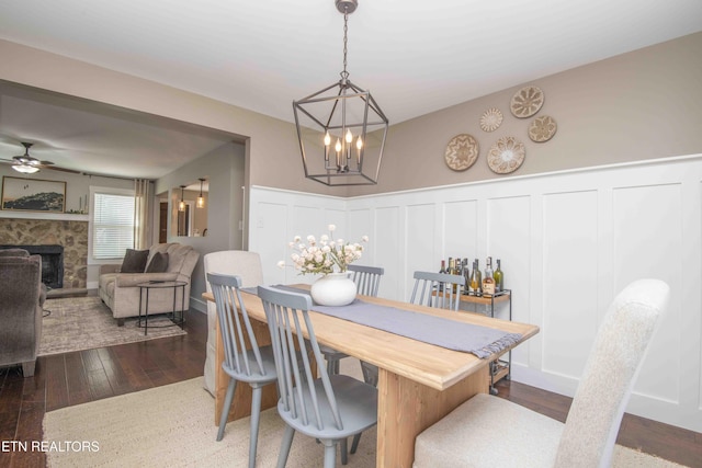 1312 Fox Ridge Dr, Powell, TN 37849 - dining space with a wainscoted wall, a fireplace with raised hearth, ceiling fan with notable chandelier, wood-type flooring, and a decorative wall