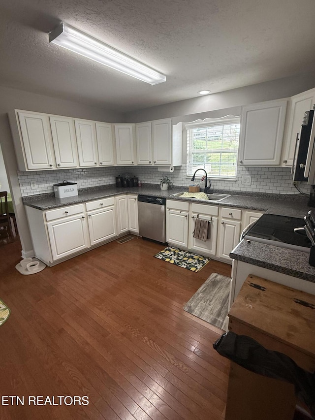 kitchen with backsplash, a sink, white cabinets, dark wood-style floors, and stainless steel appliances