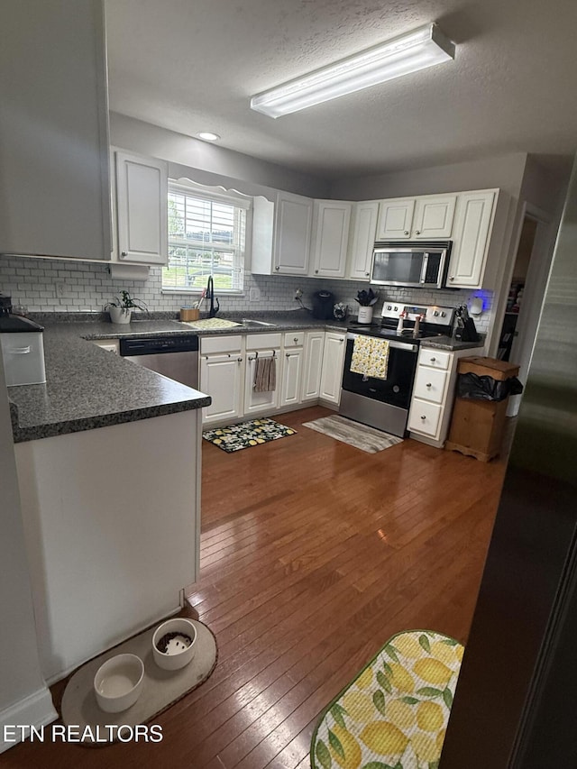 kitchen featuring dark countertops, appliances with stainless steel finishes, decorative backsplash, and a sink