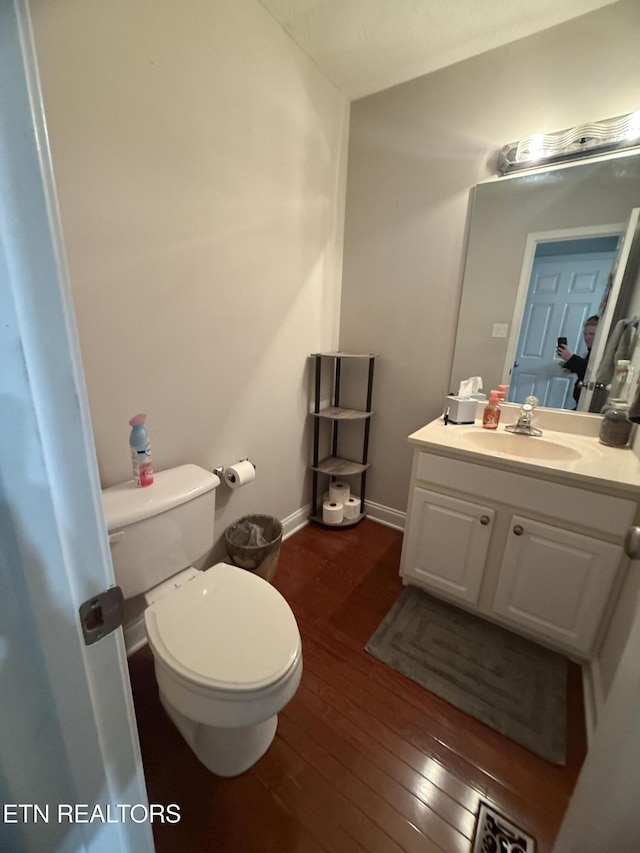 bathroom featuring vanity, baseboards, toilet, and hardwood / wood-style flooring