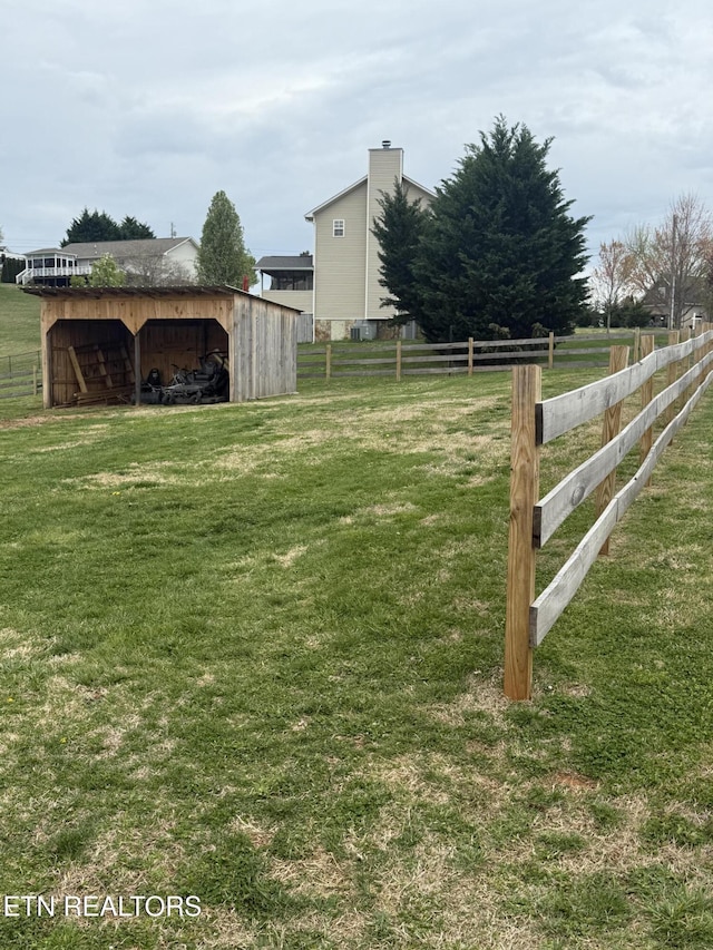 view of yard with a pole building, fence, and an outbuilding