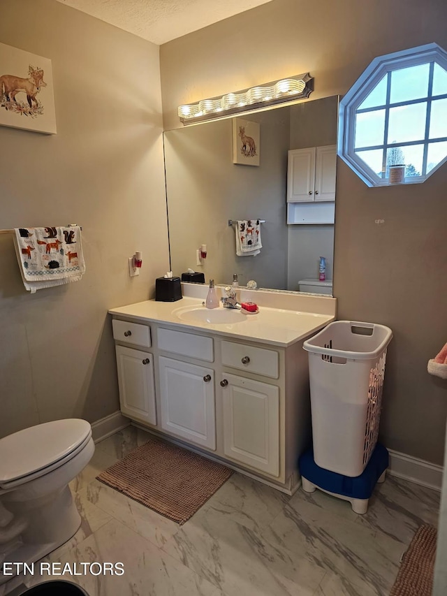 bathroom with baseboards, toilet, and marble finish floor