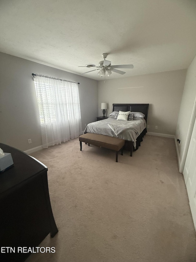 bedroom with a ceiling fan, baseboards, and light carpet