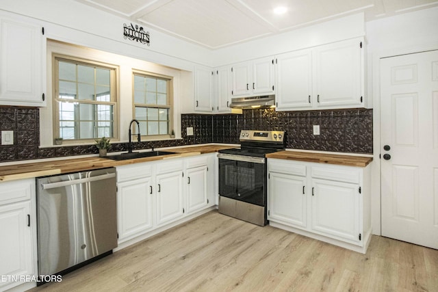 kitchen featuring white cabinetry, under cabinet range hood, a sink, wood counters, and stainless steel appliances