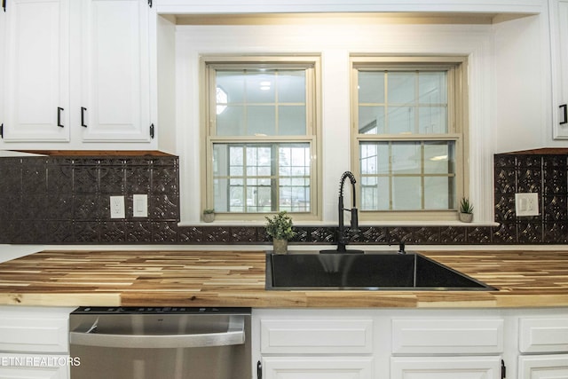 kitchen with wooden counters, dishwasher, white cabinetry, a sink, and backsplash
