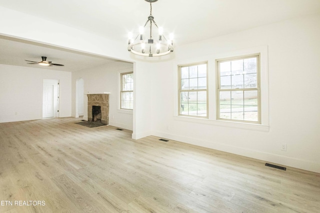 unfurnished living room featuring an inviting chandelier, baseboards, wood finished floors, a tile fireplace, and visible vents