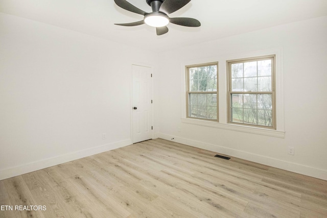 spare room with baseboards, visible vents, and wood finished floors