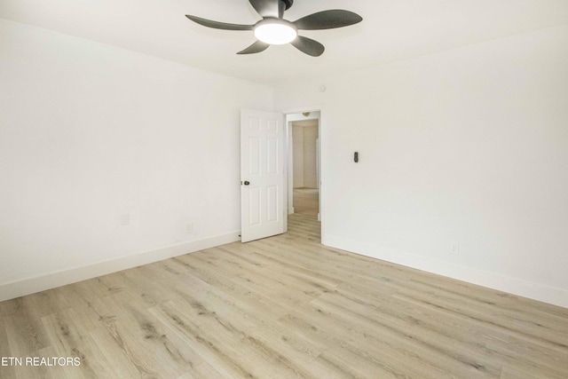 spare room featuring baseboards, a ceiling fan, and light wood finished floors