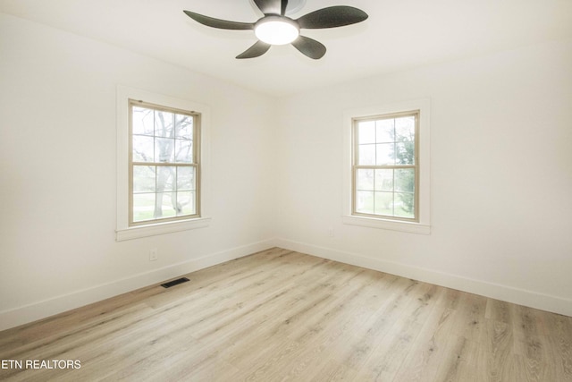 empty room featuring baseboards, ceiling fan, wood finished floors, and visible vents