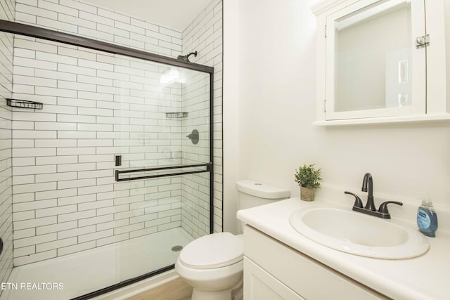 bathroom with vanity, a shower stall, and toilet