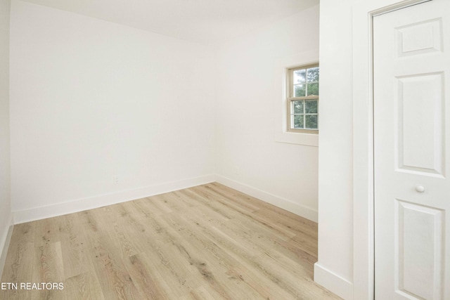 spare room with baseboards and wood finished floors