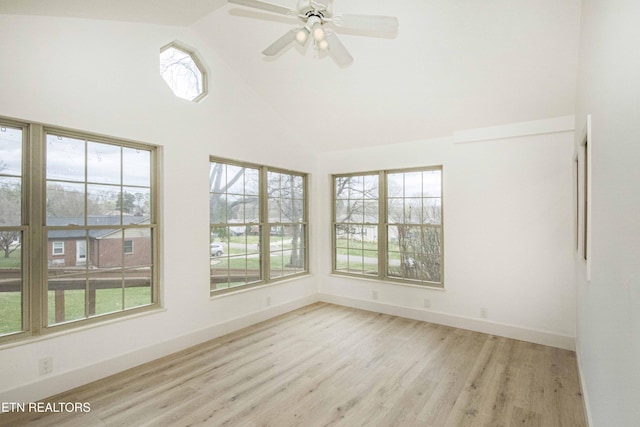 spare room with a ceiling fan, high vaulted ceiling, baseboards, and light wood-style floors