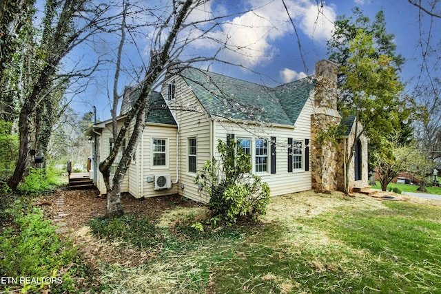 view of side of home featuring a lawn, a shingled roof, ac unit, and a chimney
