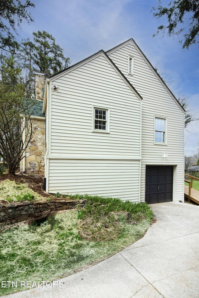 view of side of property with concrete driveway and a garage
