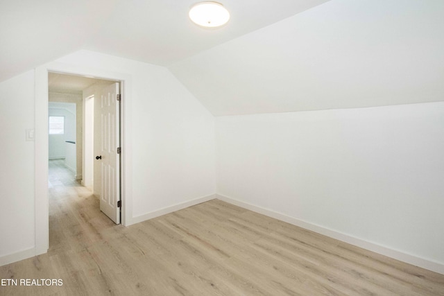 bonus room featuring baseboards, vaulted ceiling, and light wood-style flooring